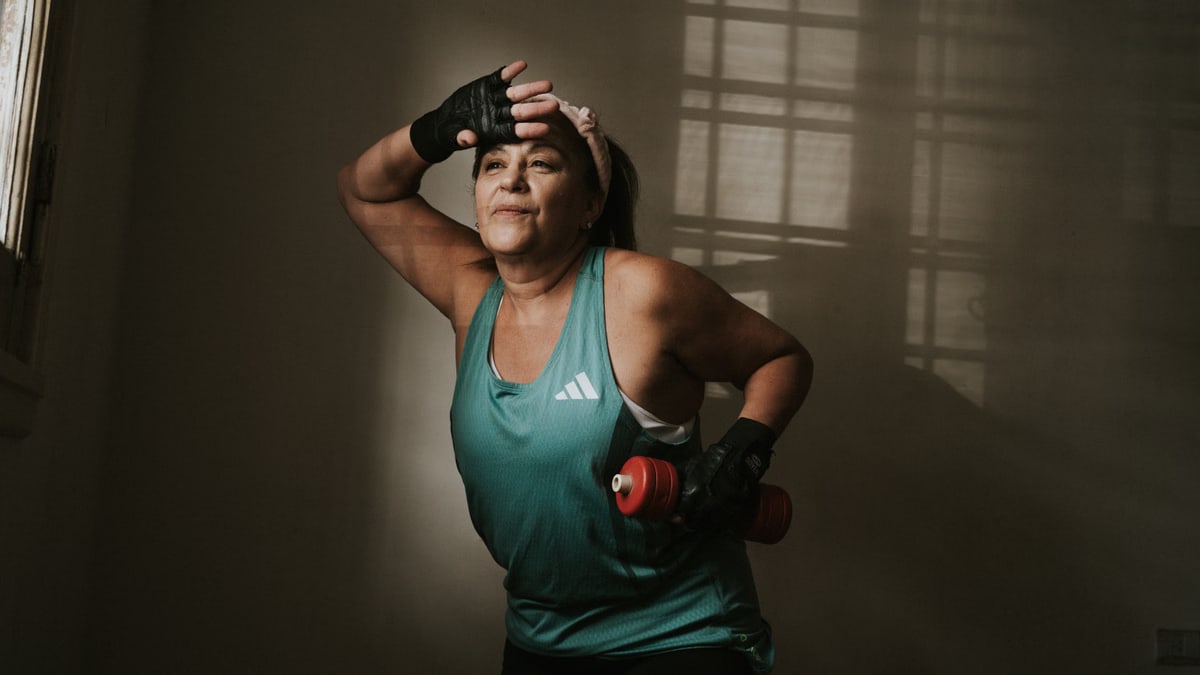 Middle-aged woman working out with a dumbbell indoors. Fitness and healthy lifestyle concept.